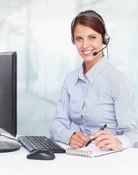 A businesswoman writing notes and wearing a headset